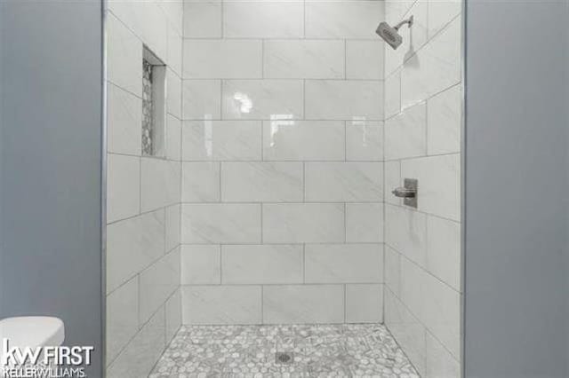 bathroom featuring toilet and a tile shower