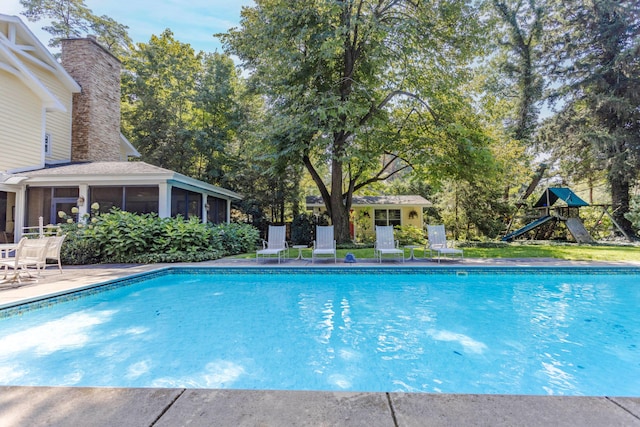 view of pool featuring a playground and a sunroom