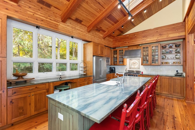 kitchen featuring range, a kitchen island with sink, high quality fridge, wooden ceiling, and wall chimney exhaust hood