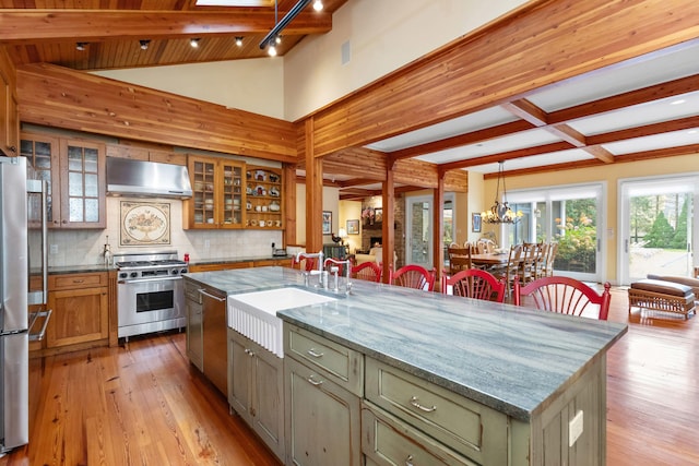 kitchen with light stone counters, light wood-type flooring, an island with sink, and appliances with stainless steel finishes