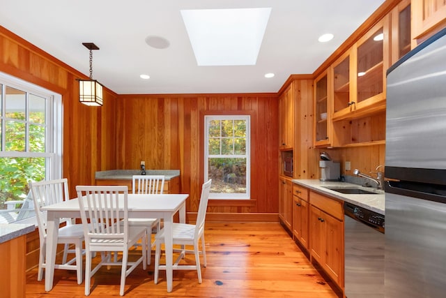 kitchen with appliances with stainless steel finishes, plenty of natural light, decorative light fixtures, sink, and light stone countertops