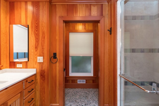 bathroom featuring vanity, wooden walls, and an enclosed shower