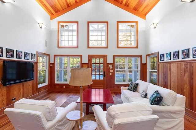 living room with wood-type flooring, wooden ceiling, high vaulted ceiling, and wood walls