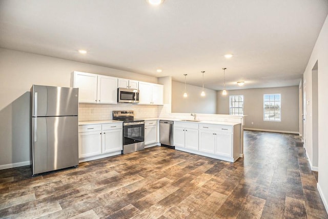 kitchen featuring stainless steel appliances, hanging light fixtures, white cabinets, and kitchen peninsula