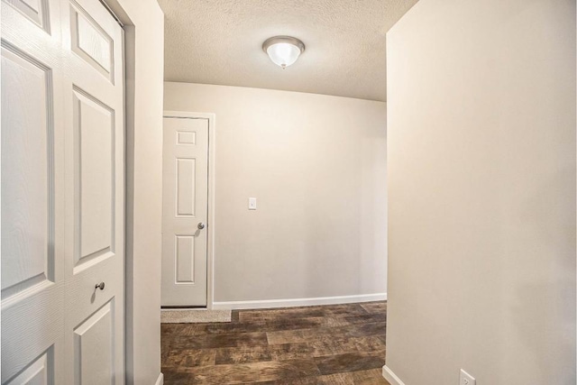 hall featuring a textured ceiling and dark hardwood / wood-style flooring