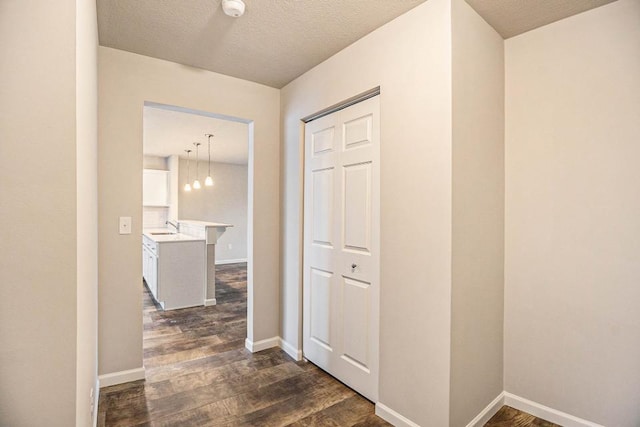 corridor featuring dark hardwood / wood-style flooring, sink, and a textured ceiling