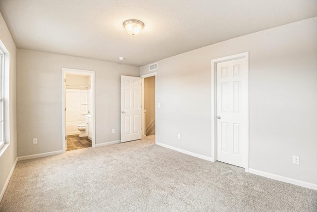 unfurnished bedroom featuring connected bathroom and carpet