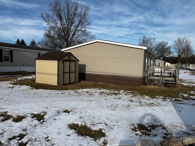 view of snow covered exterior with a deck and a storage unit