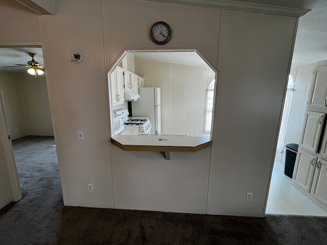 kitchen featuring white cabinetry, white appliances, a kitchen breakfast bar, and carpet