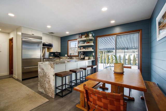 interior space featuring dark hardwood / wood-style flooring, sink, a textured ceiling, and wood walls