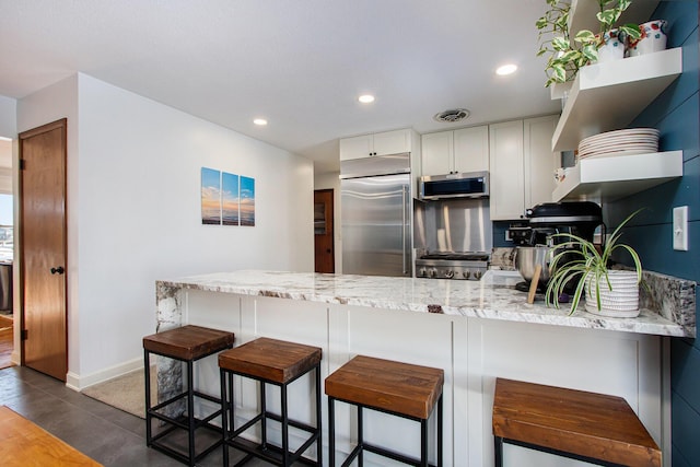 kitchen with white cabinetry, a breakfast bar area, kitchen peninsula, and appliances with stainless steel finishes