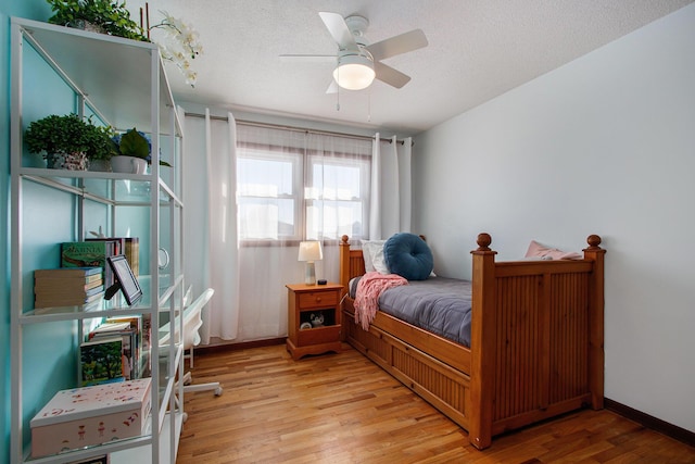 bedroom featuring ceiling fan, light hardwood / wood-style floors, and a textured ceiling