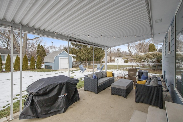 snow covered patio with area for grilling, an outdoor living space, and a storage unit