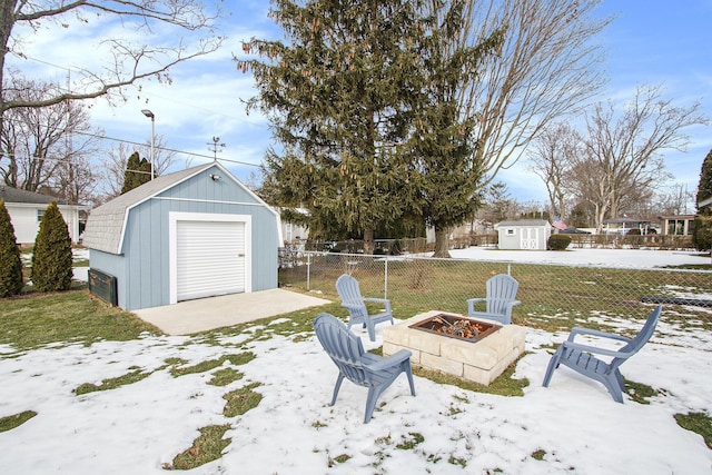 yard layered in snow featuring a shed and an outdoor fire pit