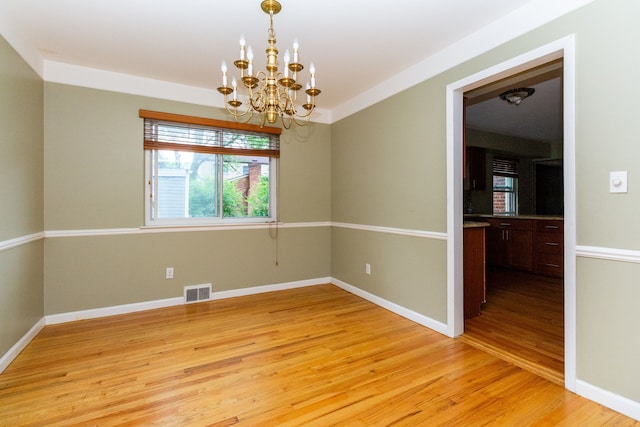 empty room featuring a chandelier and light hardwood / wood-style floors