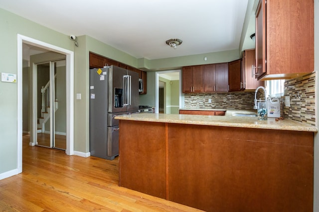 kitchen with sink, decorative backsplash, stainless steel appliances, and kitchen peninsula