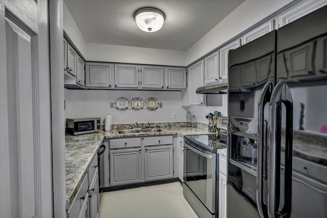 kitchen with gray cabinetry, sink, light stone countertops, and appliances with stainless steel finishes