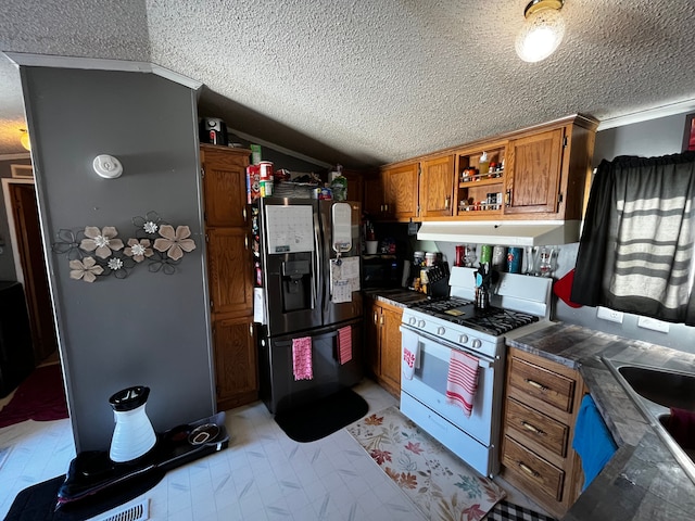 kitchen with vaulted ceiling, sink, stainless steel fridge, white range with gas stovetop, and a textured ceiling