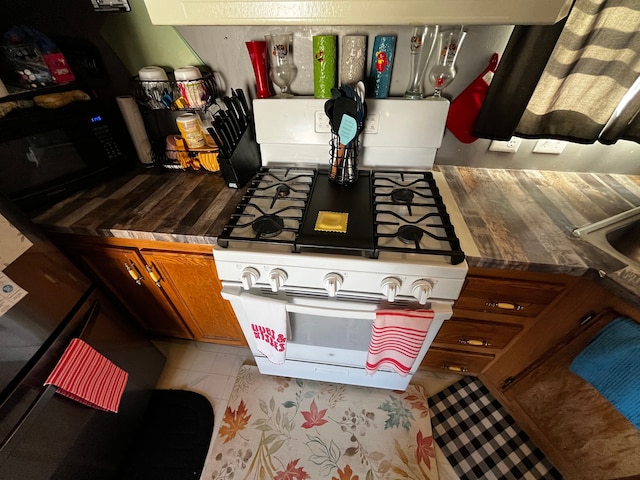 kitchen featuring tile patterned floors, white gas range, and butcher block counters