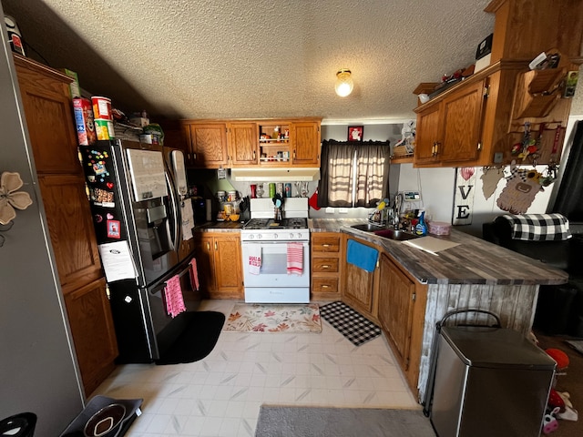 kitchen featuring sink, stainless steel fridge, white range with gas cooktop, and a textured ceiling