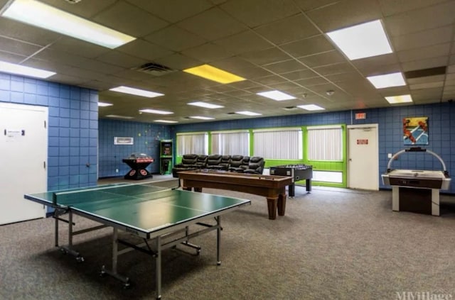 playroom with tile walls and a drop ceiling