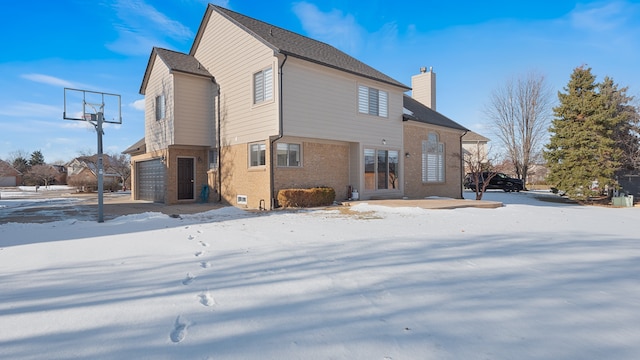 snow covered house featuring a garage