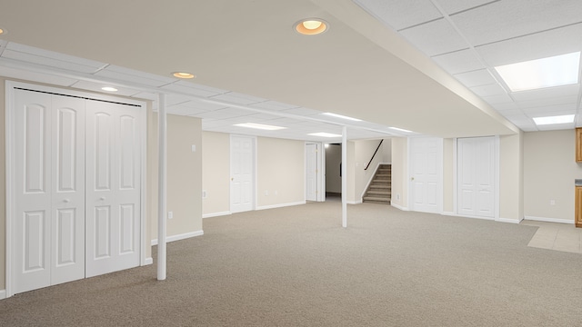 basement featuring light colored carpet and a drop ceiling