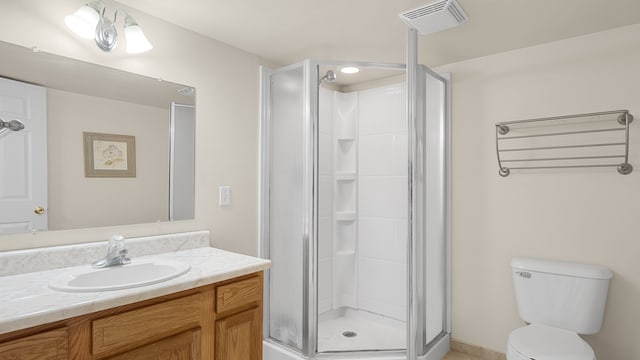 bathroom featuring vanity, a shower with shower door, and toilet