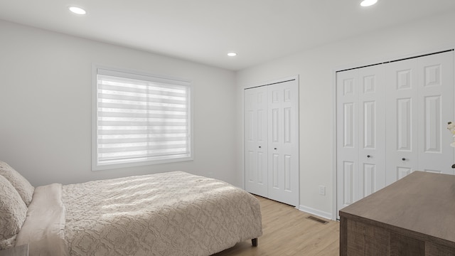 bedroom with multiple closets and light wood-type flooring