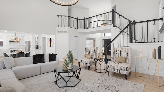 living room with light wood-type flooring, a high ceiling, and a notable chandelier