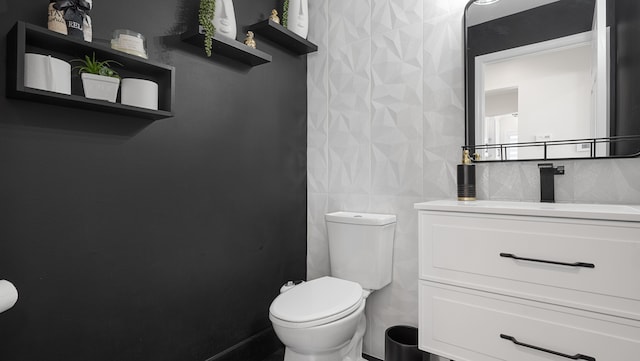 bathroom with vanity, toilet, and tile walls