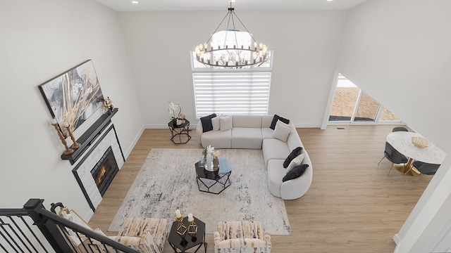 living room with a towering ceiling, a notable chandelier, and light wood-type flooring