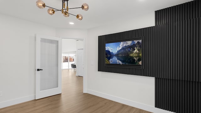 unfurnished room featuring wood-type flooring and a notable chandelier