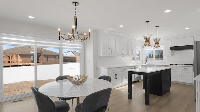 kitchen with hanging light fixtures, white cabinetry, a kitchen island, and black cooktop