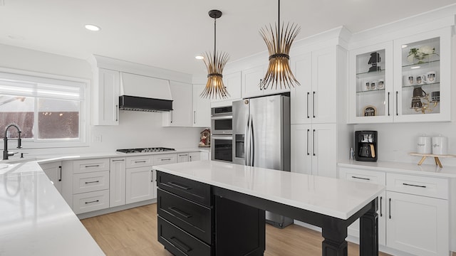 kitchen featuring stainless steel appliances, custom exhaust hood, hanging light fixtures, and white cabinets