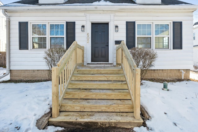 snow covered property entrance featuring roof with shingles