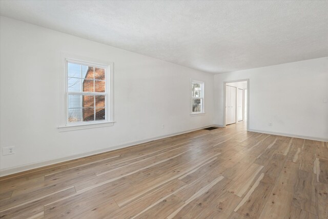 spare room featuring a textured ceiling and light hardwood / wood-style flooring