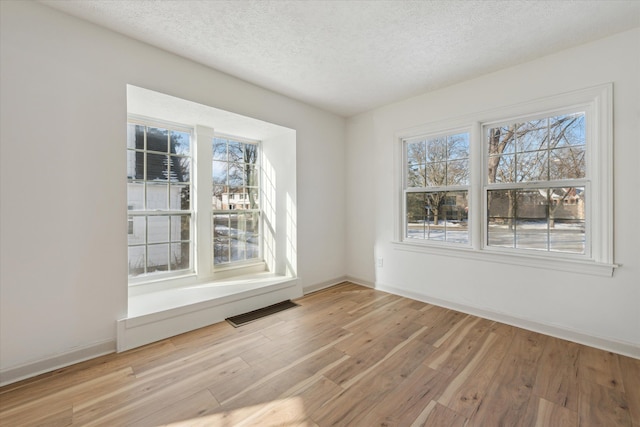 unfurnished dining area featuring light hardwood / wood-style flooring and a textured ceiling