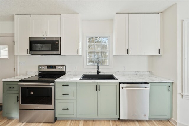 kitchen featuring white cabinetry, sink, stainless steel appliances, and green cabinets