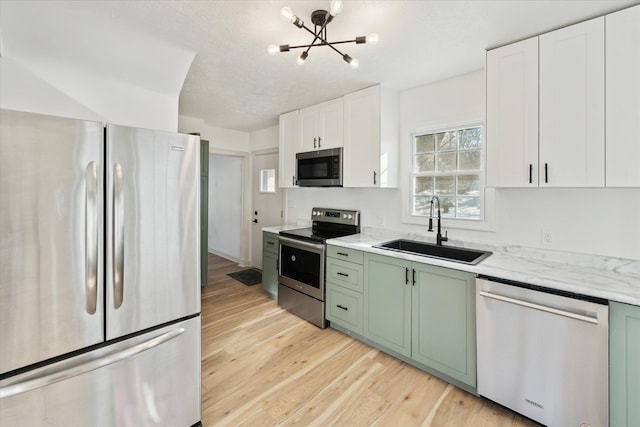 kitchen featuring sink, white cabinets, green cabinetry, stainless steel appliances, and light wood-type flooring