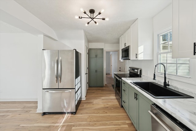 kitchen with sink, light hardwood / wood-style flooring, green cabinets, stainless steel appliances, and white cabinets