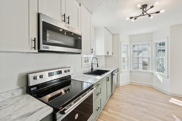 kitchen featuring appliances with stainless steel finishes, sink, white cabinets, a textured ceiling, and light hardwood / wood-style flooring