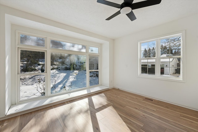 spare room with visible vents, a textured ceiling, a healthy amount of sunlight, and wood finished floors