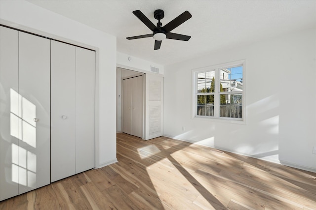 unfurnished bedroom featuring visible vents, light wood-style flooring, and a ceiling fan