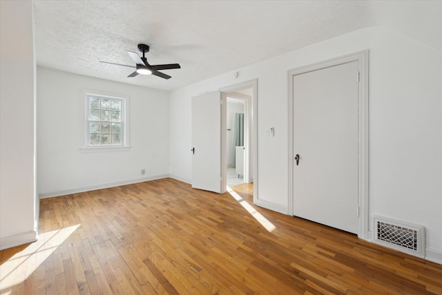 empty room featuring ceiling fan, hardwood / wood-style flooring, and a textured ceiling