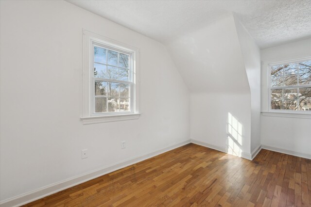 bonus room featuring lofted ceiling, dark hardwood / wood-style floors, a textured ceiling, and a wealth of natural light