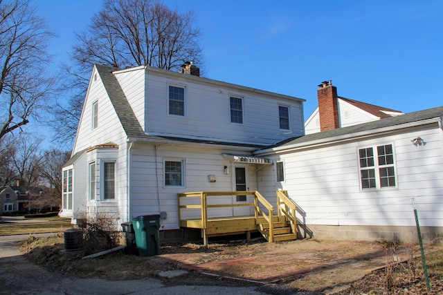 back of house featuring a shingled roof and a chimney