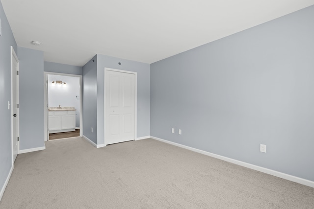 unfurnished bedroom featuring ensuite bathroom, light carpet, and a closet