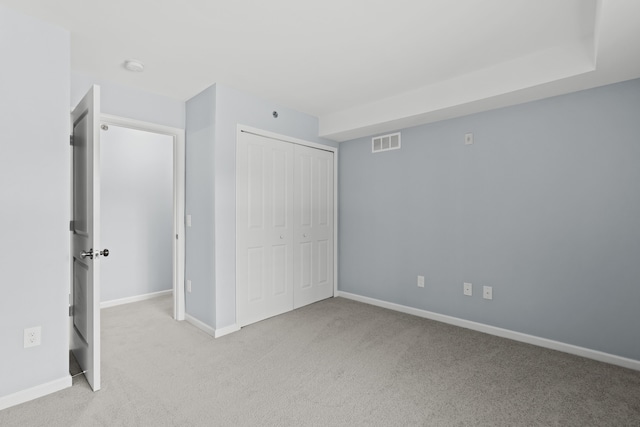 unfurnished bedroom featuring light carpet and a closet