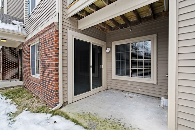 snow covered property entrance with a patio